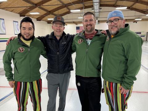 Four male curlers standing on the ice